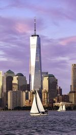 Sailboat in sea against modern buildings in city