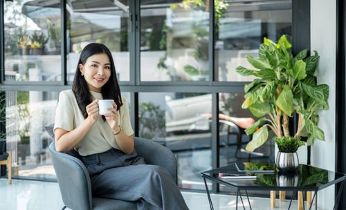 Young woman using mobile phone while sitting in cafe