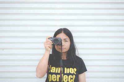 Portrait of young woman standing against wall