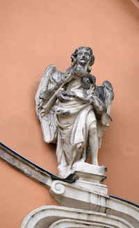 Low angle view of angel statue against wall