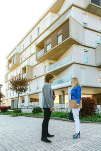 Full length side view of woman standing against building