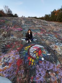 Woman on multi colored umbrella against sky