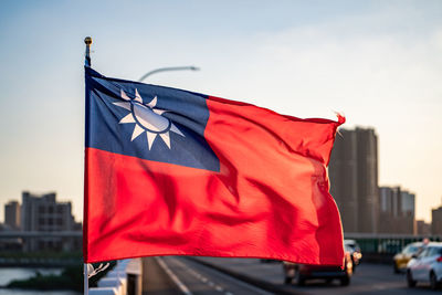 Red flag against building in city against sky