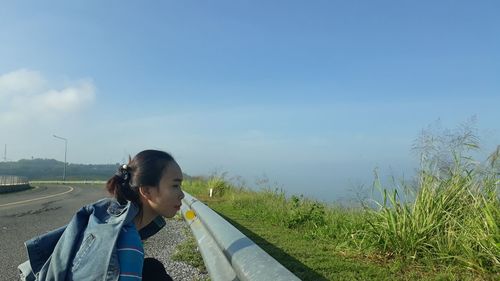 Woman smiling on road amidst field against sky