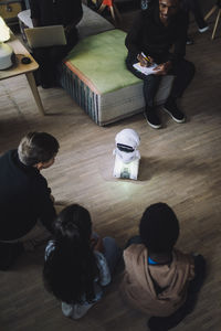 High angle view of multiracial children sitting in front of social robot in innovation lab