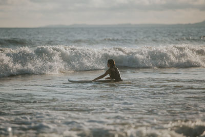 Woman surfing in sea against sky