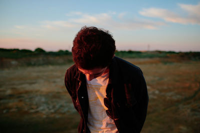 Side view of young man standing against sky