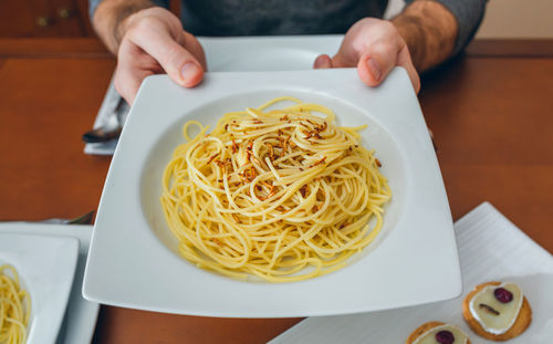 Cropped image of man having noodles and worms in restaurant