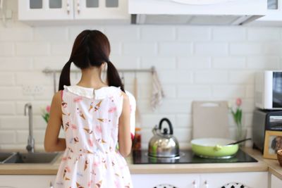 Young woman holding camera in kitchen