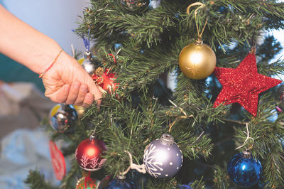 Cropped hand decorating christmas tree