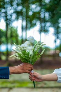 Cropped hands of couple holding white flower bouquet