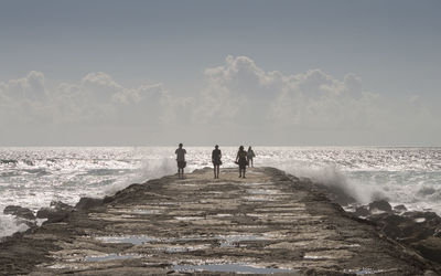 People standing on beach against sky