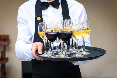 Close-up of waiter holding drinks in tray at restaurant