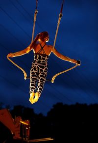 Low angle view of woman jumping over rope against sky