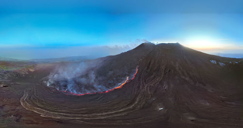 Etna erupting top view with lava flow and smoke-blue sky during blue hour- aerial panorama at sunset