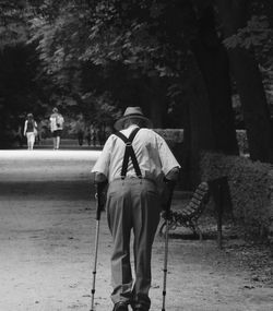 Rear view of senior man walking with cane in park