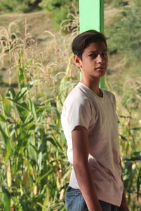 Portrait of young man standing against crops