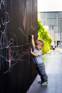 Full length of cute boy drawing on black wall