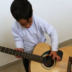 Boy playing guitar by wall