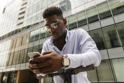 Young man using mobile phone in front of building