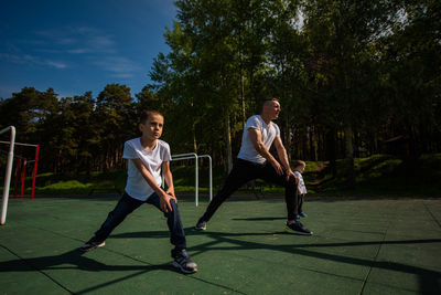 Full length of men playing on field against trees