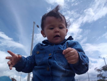 Portrait of boy holding camera against sky