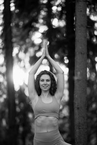 Young woman standing against trees