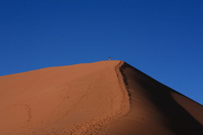 Distance shot of man walking at desert