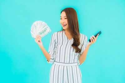 Young woman holding umbrella against blue background