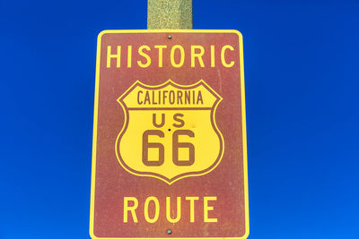 Close-up of warning sign against clear blue sky