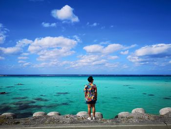 Rear view of woman standing by sea