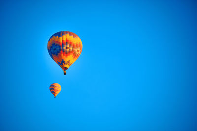 Low angle view of hot air balloons against clear blue sky