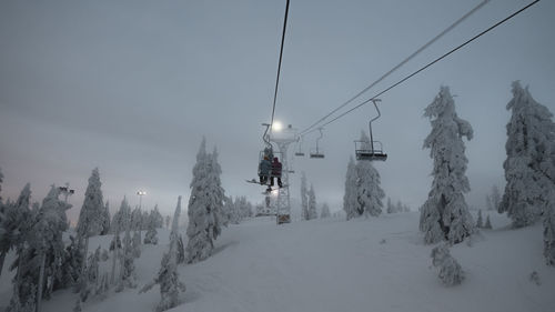 Ski lift over snow covered mountains against sky