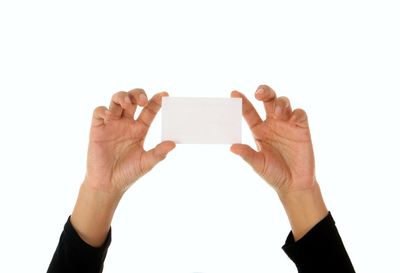 Close-up of hand holding smart phone against white background