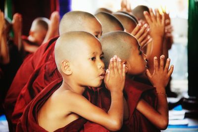 Novice buddhist monks with hands clasped praying in temple