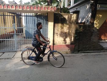 Side view of man riding bicycle on road in city