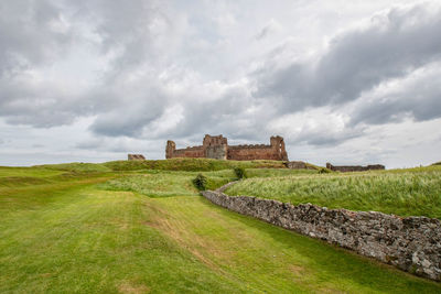 Old ruin on landscape against cloudy sky