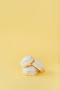 Delicious lemon iced cookies stacked on yellow backdrop