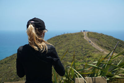 Rear view of woman standing on field against sky