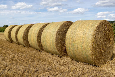 Hay bales on field against sky