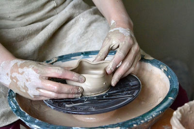 Person potter makes clay earthen pot on a potter's wheel in pottery workshop person