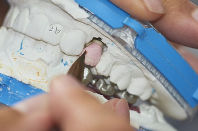 Close-up of person using paintbrush while molding dentures