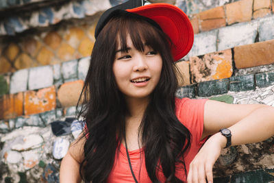 Portrait of young woman standing against wall