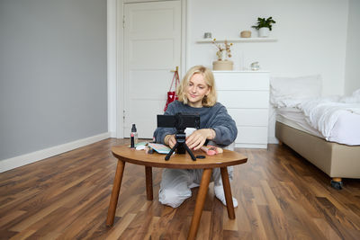Young woman using laptop while sitting on hardwood floor at home