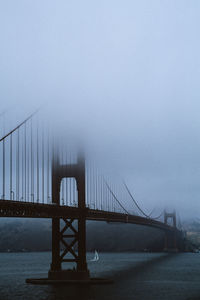 The golden gate bridge in fog with sailboat underneath