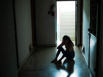 Full length of woman sitting at entrance of building