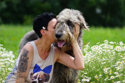 Woman kissing irish wolfhound while sitting on grassy field at park