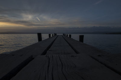 Wooden pier over sea against sky during sunset