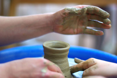 Cropped hands of people making clay pot
