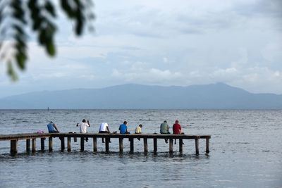 Men in sea against sky